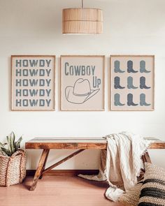 three framed cowboy posters hang on the wall above a wooden bench in a living room