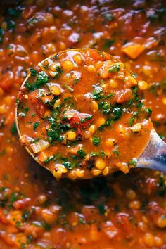 a wooden spoon filled with soup and vegetables