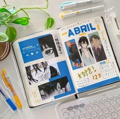 an open book sitting on top of a white desk next to a keyboard and pen