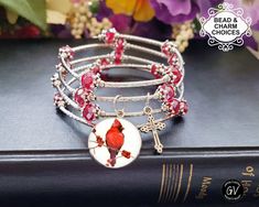 "Red Bird Cardinal, Memory Wire Beaded Bracelet, Memorial Jewelry, Remembrance Gift, Adjustable, Cross Charm, Sympathy Gift for a Friend.  Adjustable Beautiful memory wrap bracelet - 3 colors available. The beauty of any memory wire bracelet is that it can be adjusted to fit any size wrist!  One size fits all   No clasp required & it will never lose its shape! These bracelets are perfect for people who struggle to put on jewelry.  Beads range from 6 mm to 10 mm.  ♥ COLORS: RED, CLEAR, EARTHTONE, BLACK or MULIT COLORED BEADS 🚩 THE PRICE OF THE BRACELET \"INCLUDES\" THE RED BIRD CARDINAL PRINT SETTING AS SHOWN, it measures 3/4\" in diameter. It does not include photos of your loved ones.  🚩 WHEN YOU SELECT FROM THE CHARM CHOICES - YOU ARE \"ADDING\" CHARMS FROM THE CHARM CHART(s) TO ADD TO Bird Cardinal, Cardinal Print, Heart With Wings, Lace Heart, Remembrance Gifts, Bird Charm, Puffed Heart, Red Bird, Memory Wire Bracelets