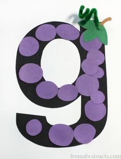 the letter g is made out of paper and has grapes hanging from it's top