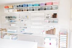 an organized craft room with white shelving and lots of craft supplies on the shelves