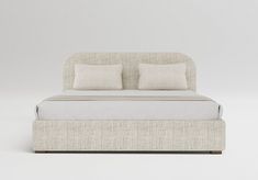 the bed has two pillows on it and is made up with linens in neutral colors