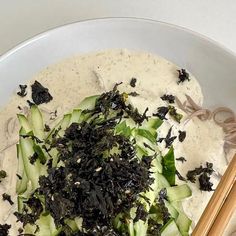 a white bowl filled with food and chopsticks on top of the bowl next to it