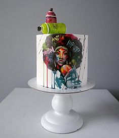 a white cake decorated with an image of a woman's face and spray paint