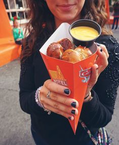 a woman is holding a box of doughnuts and a cup of orange juice