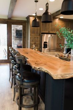 a kitchen island with stools in front of it and lights hanging from the ceiling