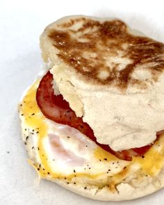 an english muffin with eggs and bacon on it sitting on top of a white paper