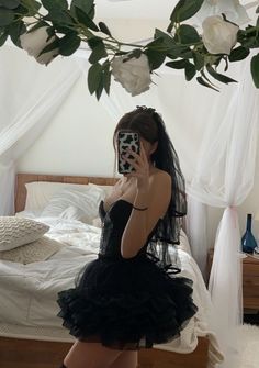 a woman is taking a selfie in her black dress and thigh high boots while sitting on a bed