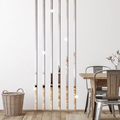 a dining room with a table and chairs in front of a white wall that has vertical bars on it