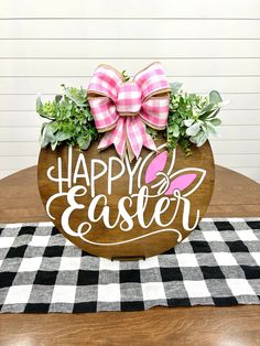 a wooden sign that says happy easter on top of a table with black and white checkered cloth