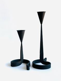 two black candlesticks sitting next to each other on top of a white surface