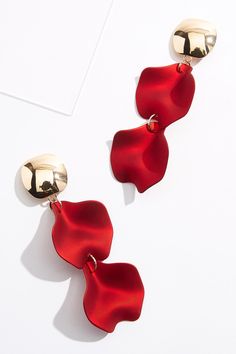 two red and gold earrings on a white surface