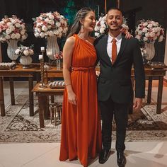 a man and woman standing next to each other in front of vases with flowers