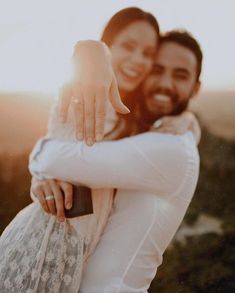 a man and woman hugging each other while the sun shines down on them behind them