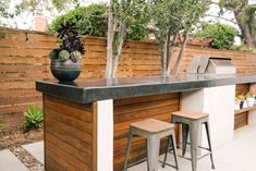 an outdoor bar with two stools and a potted plant on the counter top