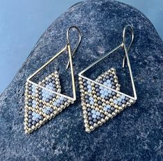 a pair of earrings sitting on top of a rock next to a blue sky background