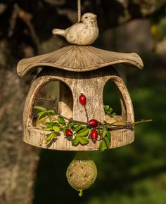 a bird feeder hanging from a tree with berries on it