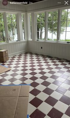 an empty room with large windows and a checkered floor in the process of remodeling