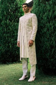 Ivory herringbone embroidered sherwani with velvet dori wave work. Comes with ivory cotton silk kurta and slim trouser.
Component: 3
Pattern: Embroidery
Type Of Work: Dori work
Neckline: Band Collar
Sleeve Type: Full sleeves
Fabric: Sherwani: Herringbone, Kurta and Pant: Cotton Silk
Color: Ivory
Other Details: 
Note: The outfit worn by the model on the left is not for sale
Occasion: Wedding - Aza Fashions Herringbone Embroidery, Ivory Sherwani, Dori Work, Embroidered Sherwani, White Kurta, Silk Kurta, Slim Trousers, Groom Outfit, Pattern Embroidery