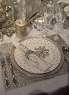 the table is set with silver and white dishes