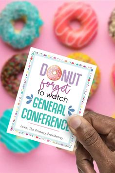 a person holding up a card that says donut day to watch general confernce