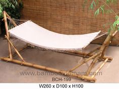 a white hammock sitting on top of a wooden stand next to a bamboo wall