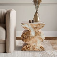 a marble table sitting next to a couch in a living room with a vase on top