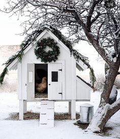 a chicken house is decorated with wreaths and garlanding around the door, as if for christmas