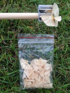 a baseball bat and some wood shavings in a bag on the ground with grass