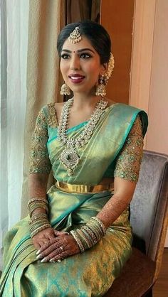 a woman in a green and gold sari sitting on a chair