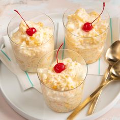 three small desserts on a plate with spoons and forks next to them,