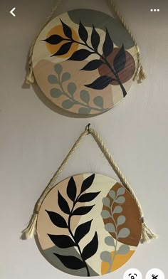 two circular wooden hangings with leaves on them, one is painted yellow and the other is brown