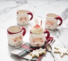 three coffee mugs decorated with santa faces and candy canes are sitting on a table