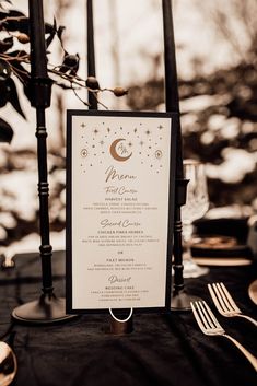 the menu card is on top of an elegant black table cloth with gold stars and moon designs