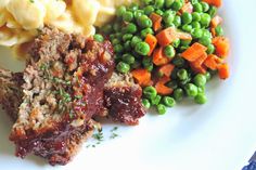 meatloaf, macaroni and peas on a plate with carrots next to it