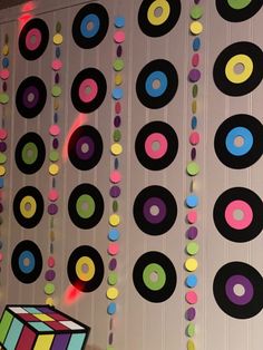 colorful circles and squares hanging from the ceiling in front of a wall with beads on it