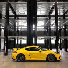 the yellow sports car is parked in front of an empty room with lots of windows