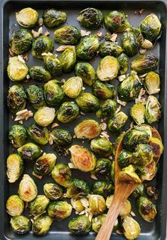 roasted brussel sprouts in a baking pan with a wooden spoon