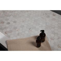 two brown bottles sitting on top of a white bath tub next to a towel and soap dispenser