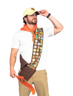 a man wearing a hat and holding an orange scarf around his neck while standing in front of a white background