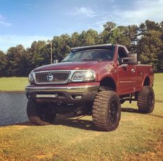 a red pick up truck parked next to a lake