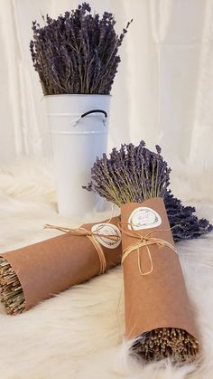 two rolls of paper wrapped in brown paper and tied with twine, sitting next to a white bucket filled with dried lavenders