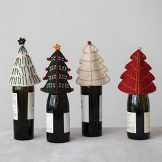 three wine bottles decorated with christmas trees