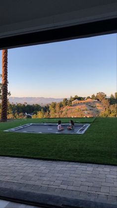 two people doing tricks on a tennis court in the middle of a yard with palm trees