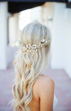 a woman with long blonde hair and flowers in her hair is wearing a white dress