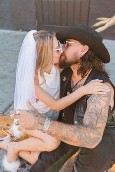 a man and woman are sitting on the ground with their arms around each other as they kiss