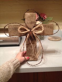 a person holding a wrapped present in front of a cross on top of a counter