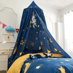 a child's bed with a blue and yellow canopy over it, which has stars on it