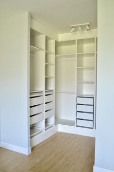 an empty room with white shelves and drawers